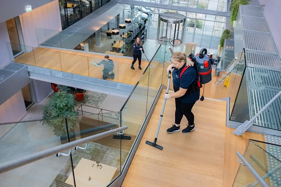 Schoonmaakster stofzuigt een atrium met trappen