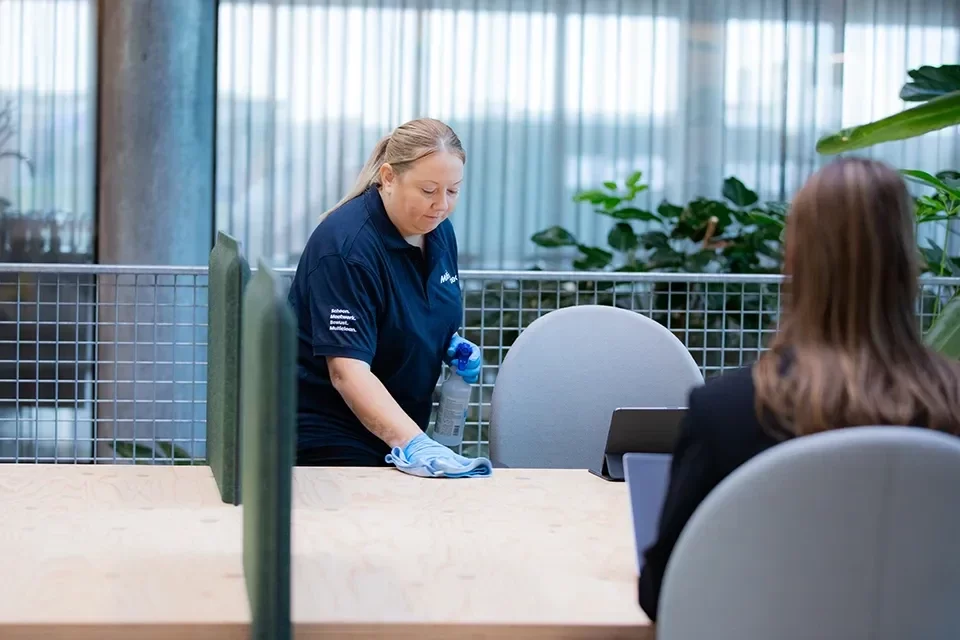 Schoonmaakster neemt een bureau af op kantoor