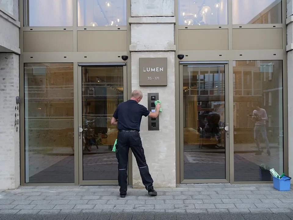Schoonmaker reinigt de entree van een appartementencomplex